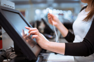 Pessoa operando tela sensível ao toque em um caixa digital, representando uma solução de frictionless retail em loja física.