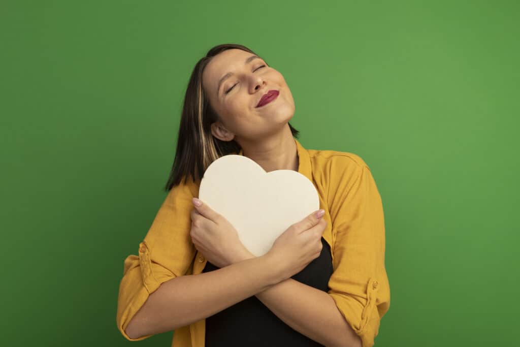 Mulher sorrindo e abraçando um coração, simbolizando o vínculo afetivo gerado por programas de fidelidade.