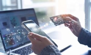 Pessoa realizando uma compra online com smartphone e cartão de crédito, com ícones digitais representando transações financeiras e tecnologia.