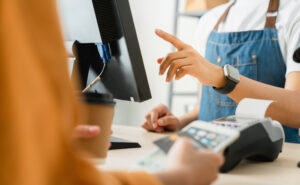 Cliente pagando com cartão de crédito em um terminal de ponto de venda (POS) em um café.