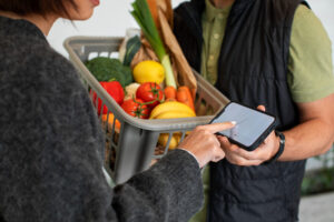 Cliente confirma a entrega de compras de supermercado em dispositivo móvel enquanto recebe uma cesta de alimentos.